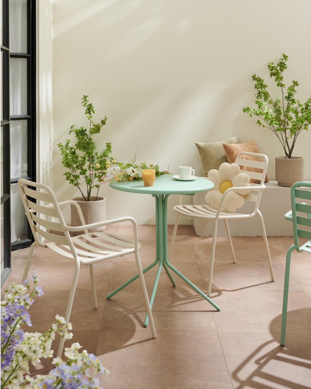 Table bistrot verte et chaises sur un patio fleuri